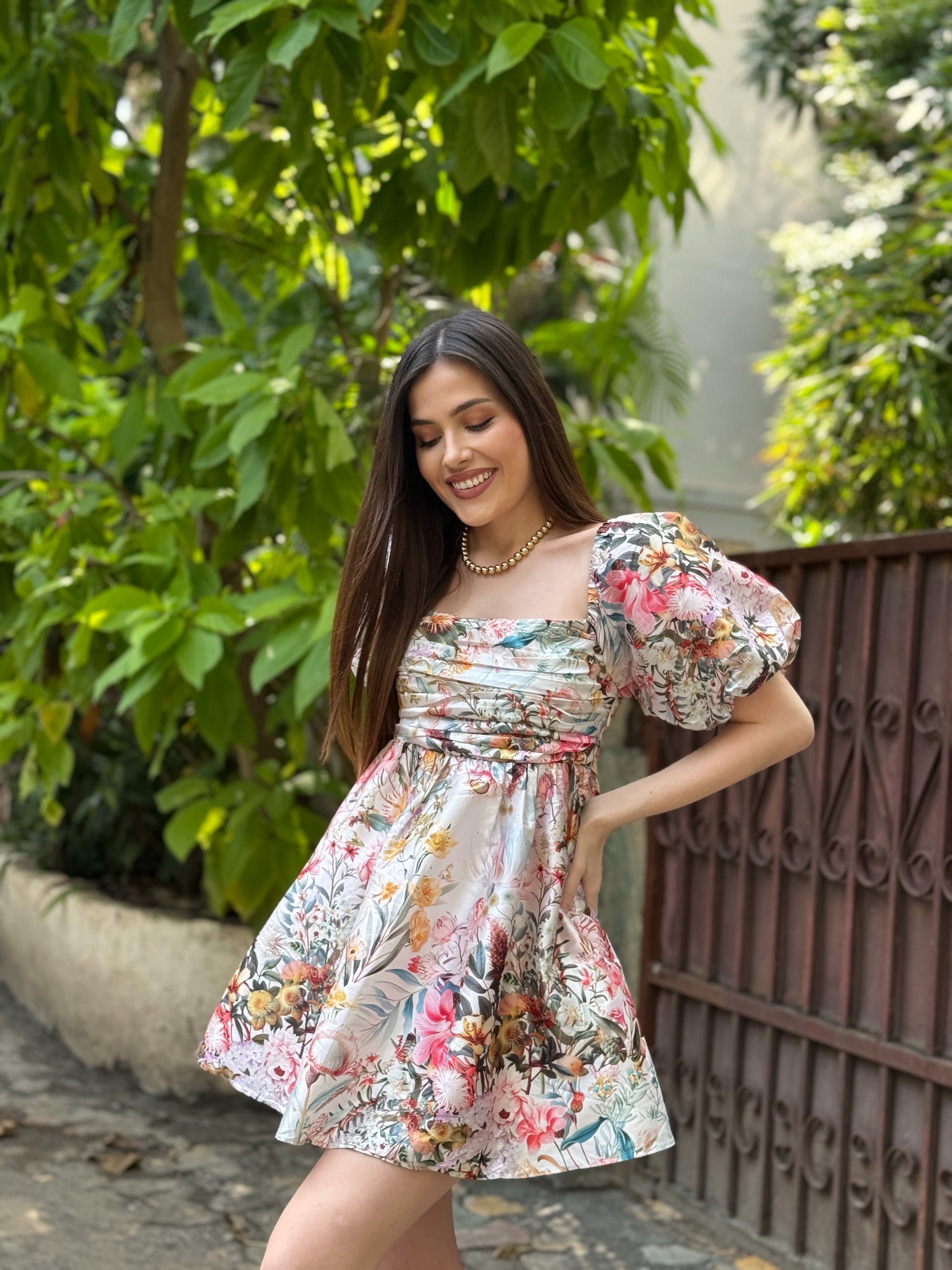 Woman in a floral dress standing outdoors with greenery in the background, western dress